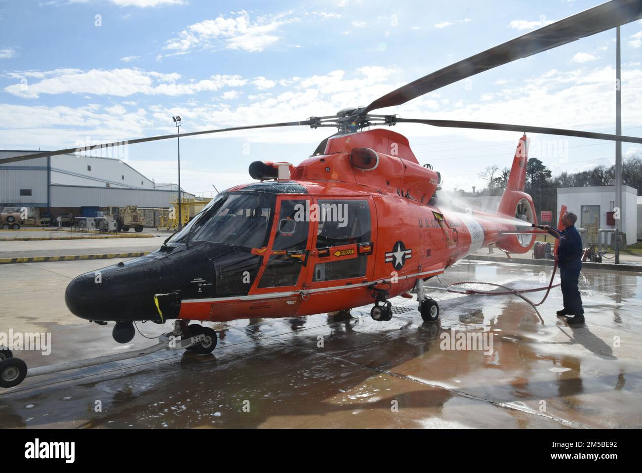 U.S. Coast Guard Petty Officer 1st Class Justin Caristo, an aviation maintenance technician assigned to the aviation engineering department at Coast Guard Air Station Savannah, Georgia, provides a fresh water wash to an MH-65 dolphin helicopter, Feb. 21, 2022. Air Station Savannah's area of responsibility cover approximately 450 miles of shoreline from the northern border of South Carolina to Melbourne, Florida. Stock Photo