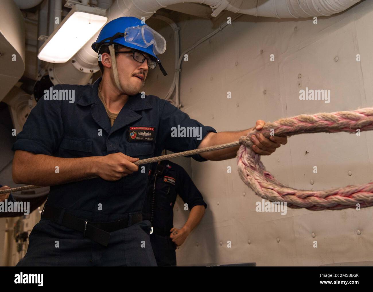 JOINT BASE PEARL HARBOR-HICKAM (Feb. 21, 2022) Boatswain’s Mate Seaman Bryan Vargas, a native of Utica, N.Y., assigned to Wasp-class amphibious assault ship USS Essex (LHD 2), heaves line during a sea and anchor evolution aboard Essex, Feb. 21, 2022. Sailors and Marines of Essex Amphibious Ready Group (ARG) and the 11th Marine Expeditionary Unit (MEU) are underway conducting routine operations in U.S. 3rd Fleet. Stock Photo