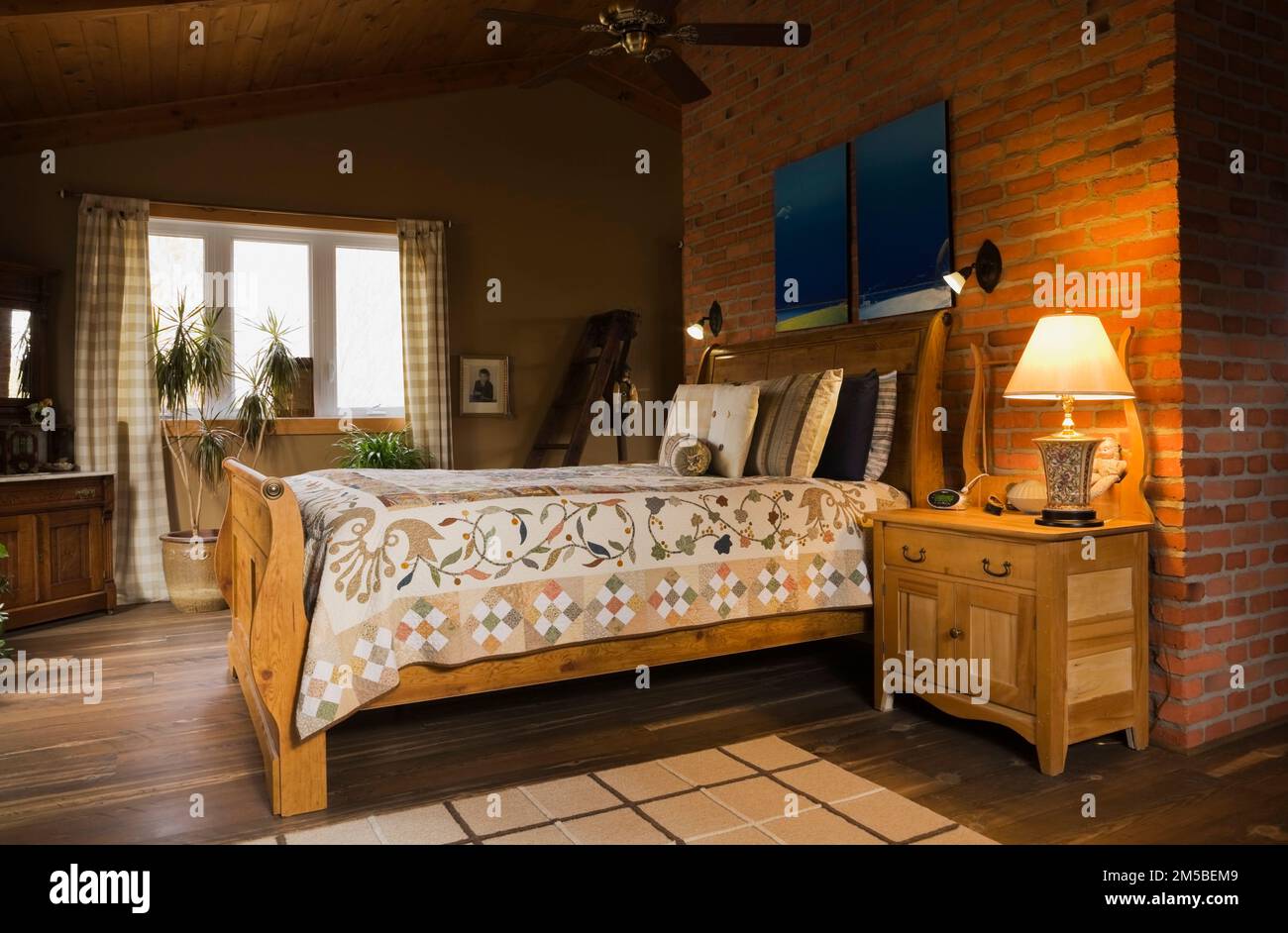 Antique wooden sleigh bed in master bedroom on upstairs floor inside country cottage style log home. Stock Photo