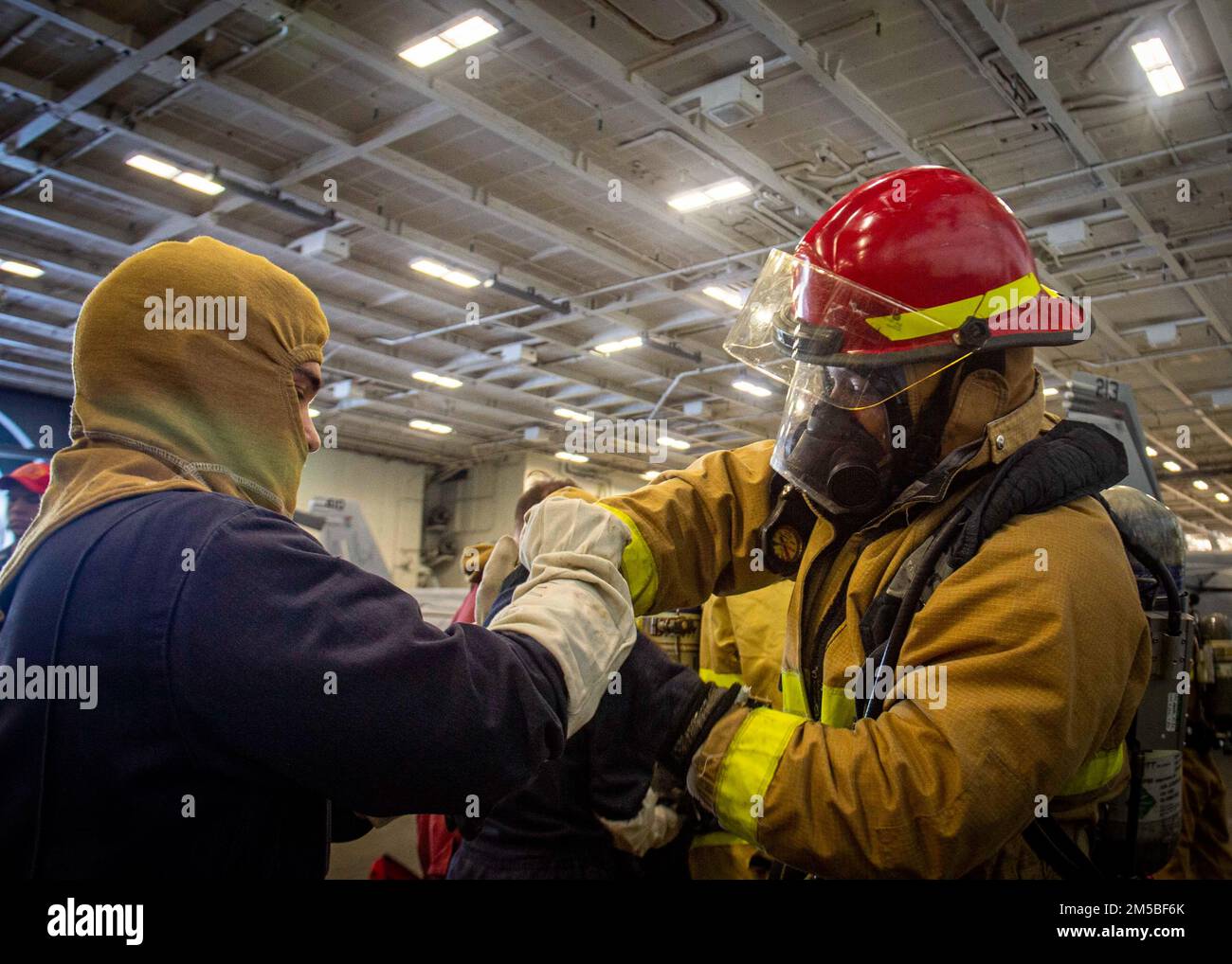 220221-N-SY758-1007 ATLANTIC OCEAN (Feb. 21, 2022) Sailors assigned to USS George H.W. Bush (CVN 77) don firefighting gear during a damage control drill for Tailored Ship’s Training Availability/Final Evaluation Problem (TSTA/FEP), Feb. 21, 2022. TSTA/FEP is a multi-phase training evolution designed to give the crew a solid foundation of unit-level operating proficiency and to enhance the ship’s ability to self-train. George H.W. Bush provides the national command authority flexible, tailorable war fighting capability through the carrier strike group that maintains maritime stability and secur Stock Photo