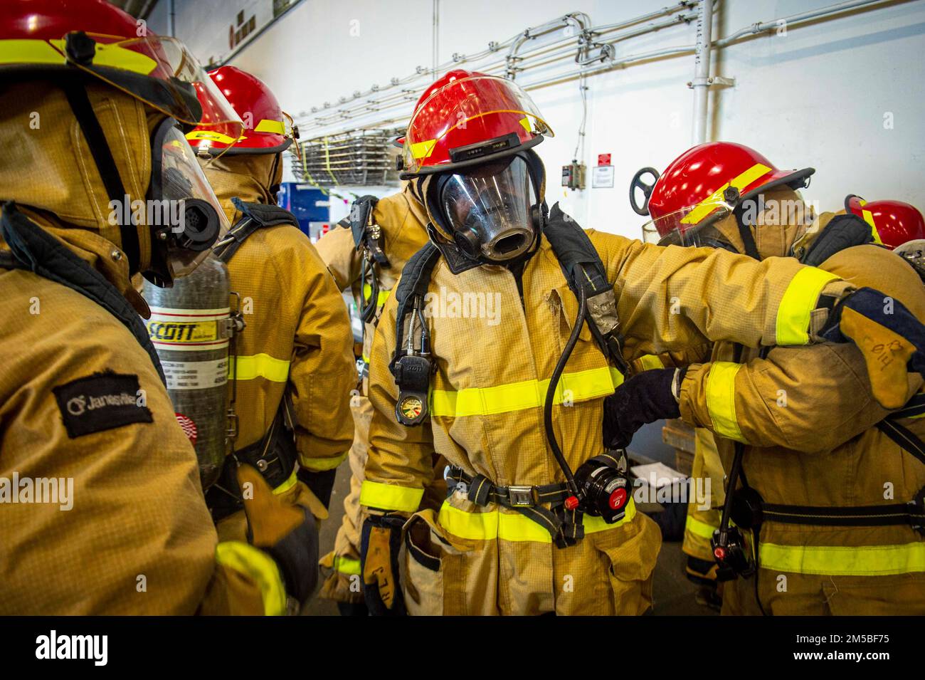 220221-N-SY758-1010 ATLANTIC OCEAN (Feb. 21, 2022) Sailors assigned to USS George H.W. Bush (CVN 77) don firefighting gear during a damage control drill for Tailored Ship’s Training Availability/Final Evaluation Problem (TSTA/FEP), Feb. 21, 2022. TSTA/FEP is a multi-phase training evolution designed to give the crew a solid foundation of unit-level operating proficiency and to enhance the ship’s ability to self-train. George H.W. Bush provides the national command authority flexible, tailorable war fighting capability through the carrier strike group that maintains maritime stability and secur Stock Photo