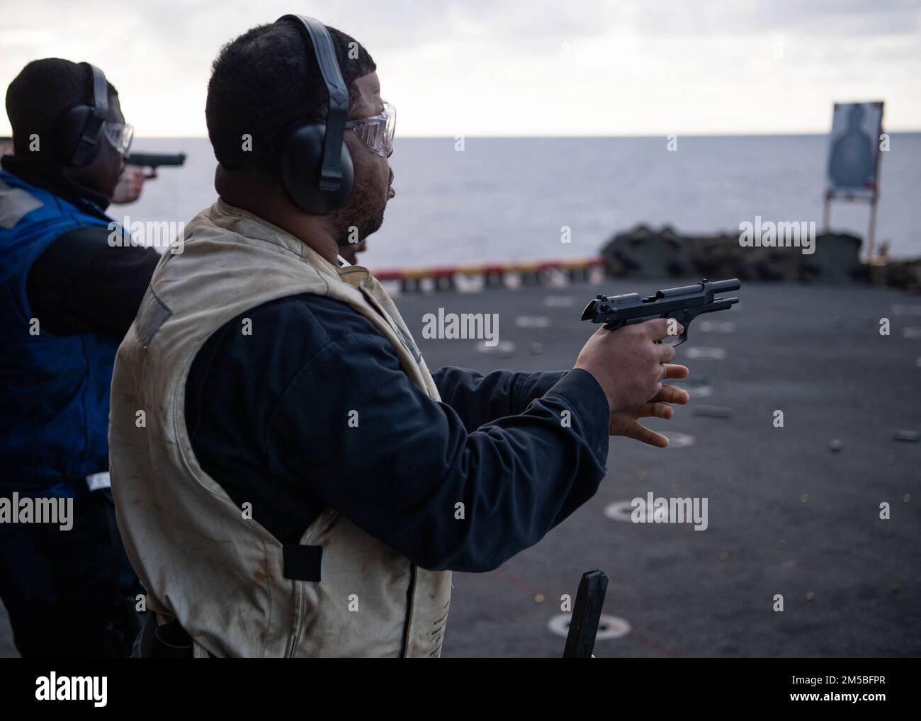 PACIFIC OCEAN (Feb. 22, 2022) Operations Specialist 1st Class Charles Powell, a native of Fort Worth, Texas, assigned to Wasp-class amphibious assault ship USS Essex (LHD 2), reloads an M9 service pistol aboard Essex during a small arms gun shoot, Feb. 22, 2022. Sailors and Marines of Essex Amphibious Ready Group (ARG) and the 11th Marine Expeditionary Unit (MEU) are underway conducting routine operations in U.S. 3rd Fleet. Stock Photo