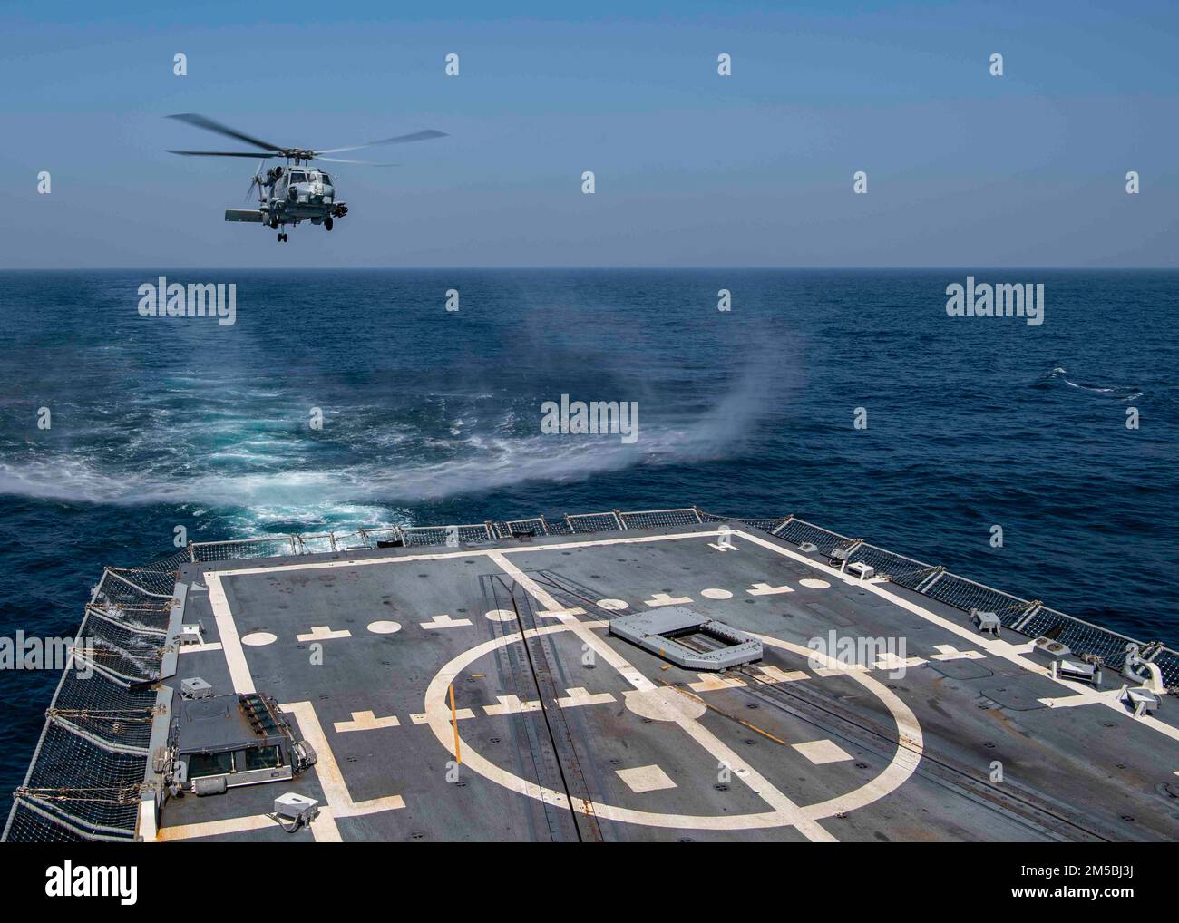 GULF OF OMAN (Feb. 23, 2022) An MH-60R Sea Hawk helicopter, attached to the “Raptors” of Helicopter Maritime Strike Squadron (HSM) 71, approaches the flight deck of guided-missile destroyer USS Gridley (DDG 101) in the Gulf of Oman, Feb. 23. Gridley is deployed to the U.S. 5th Fleet area of operations in support of naval operations to ensure maritime stability and security in the Central Region, connecting the Mediterranean and Pacific through the Western Indian Ocean and three strategic choke points. Stock Photo
