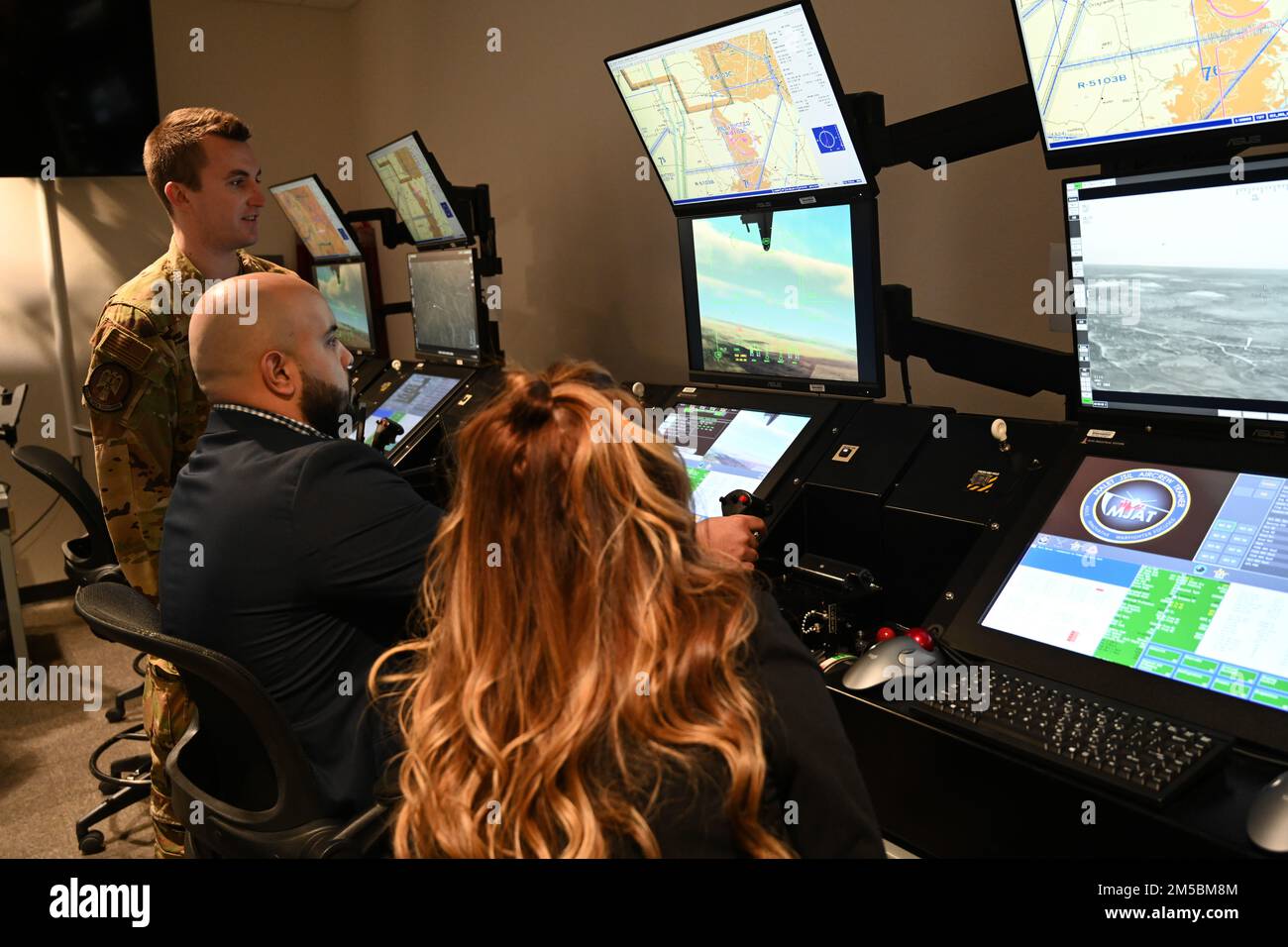 (From left to right) Capt. Brian Williams, 29th Attack Squadron instructor pilot, instructs Oliver Riquelme, military legislative assistant and Maj. Yvette Coddington, defense fellow, Feb. 22, 2022 on Holloman Air Force Base, New Mexico. Prior to the simulator, Requelme and Coddington were able to learn about the MQ-9 and its capabilities. Stock Photo