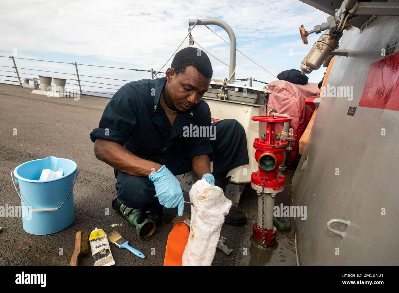 SOUTH CHINA SEA (Feb. 23, 2022) Damage Controlman 3rd Class Kouassi Date, from Dallas, conducts maintenance on a fireman plug aboard Arleigh Burke-class guided-missile destroyer USS Ralph Johnson (DDG 114). Ralph Johnson is assigned to Task Force 71/Destroyer Squadron (DESRON) 15, the Navy’s largest forward-deployed DESRON and the U.S. 7th fleet’s principal surface force. Stock Photo