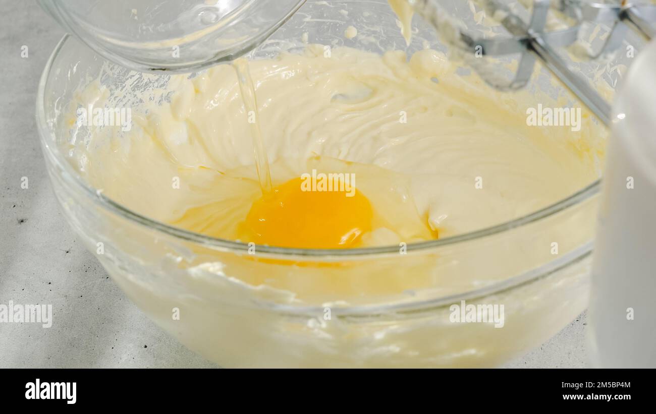 Cream cheese, eggs, and sugar in a bowl. Cheesecake recipe, mixing