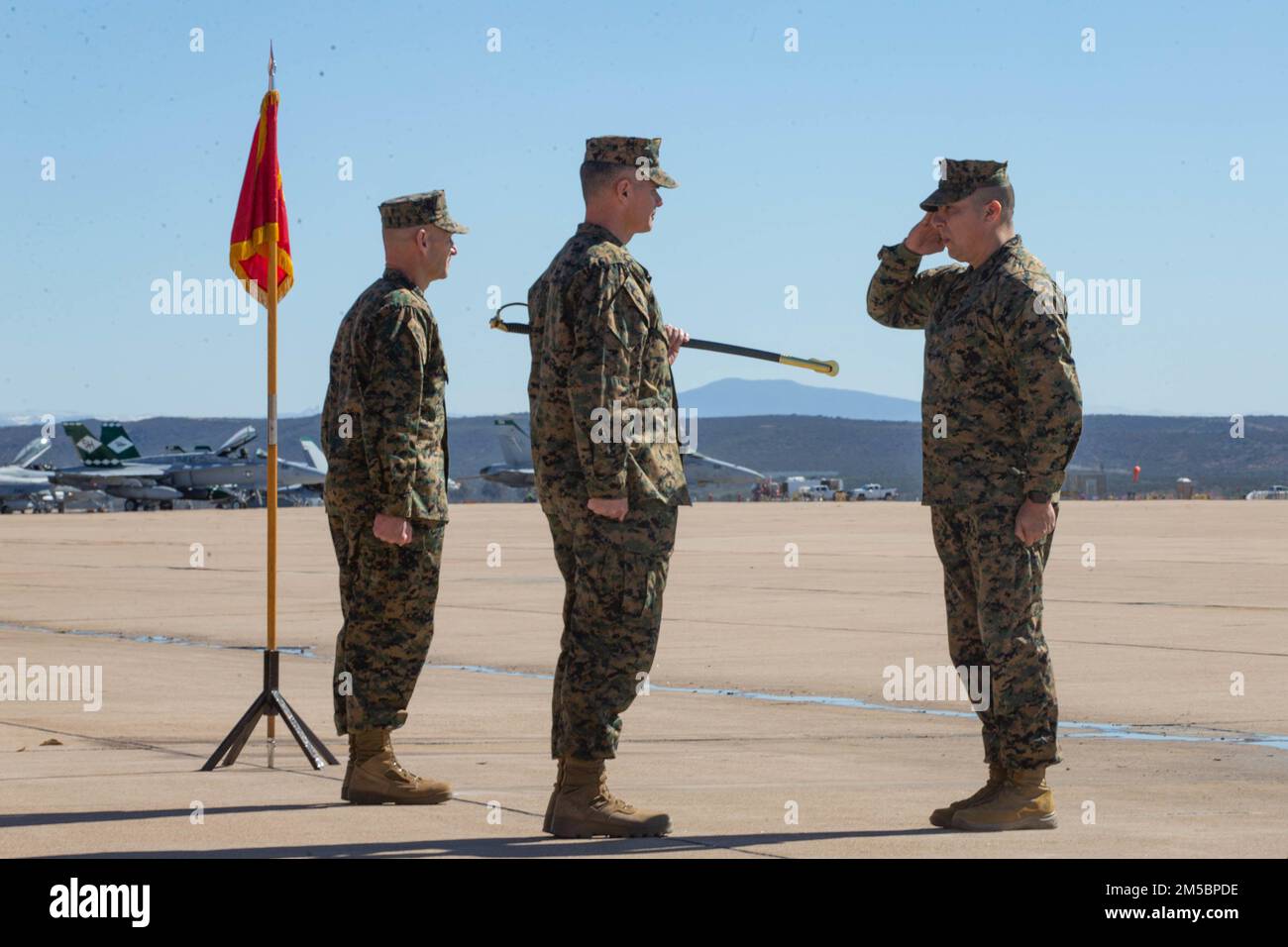 U.S. Marine Corps Sgt. Maj. Gerardo C. Ybarra, right, incoming sergeant major of Marine Air Control Group (MACG) 38, 3rd Marine Aircraft Wing, salutes Col. Jeremy S. Winters, center, commanding officer of MACG-38, before exchanging the noncommissioned officer sword during a relief and appointment ceremony on Marine Corps Air Station Miramar, California, Feb 24, 2022. A relief and appointment ceremony is a time-honored tradition, which formally signifies the transfer of responsibility and entails the total accountability and authority from one individual to another. Stock Photo