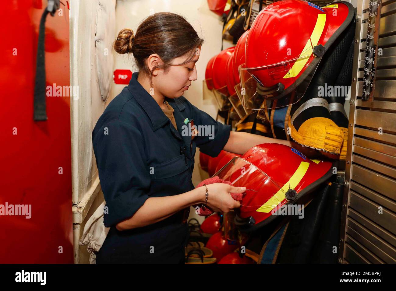 PHILIPPINE SEA (Feb. 24, 2022) Damage Controlman Fireman Michelle Romo, from Rancho Cucamonga, Calif., inspects firefighting equipment in a repair locker aboard the Nimitz-class aircraft carrier USS Abraham Lincoln (CVN 72). Abraham Lincoln Strike Group is on a scheduled deployment in the U.S. 7th Fleet area of operations to enhance interoperability through alliances and partnerships while serving as a ready-response force in support of a free and open Indo-Pacific region. Stock Photo
