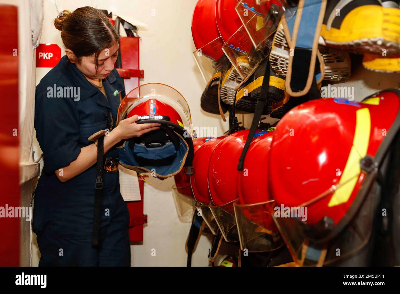 PHILIPPINE SEA (Feb. 24, 2022) Damage Controlman Fireman Michelle Romo, from Rancho Cucamonga, Calif., inspects firefighting equipment in a repair locker aboard the Nimitz-class aircraft carrier USS Abraham Lincoln (CVN 72). Abraham Lincoln Strike Group is on a scheduled deployment in the U.S. 7th Fleet area of operations to enhance interoperability through alliances and partnerships while serving as a ready-response force in support of a free and open Indo-Pacific region. Stock Photo
