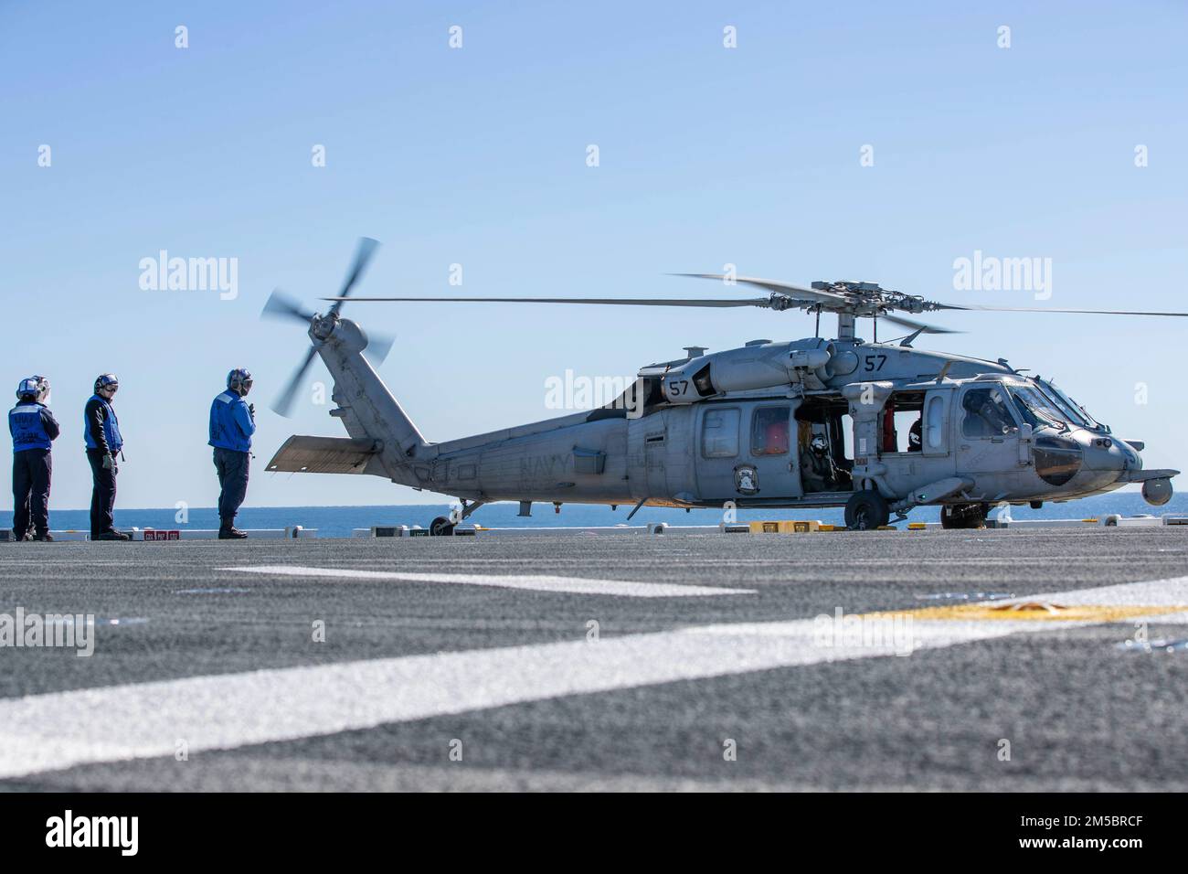 220224-N-CZ759-2016 PACIFIC OCEAN (Feb. 24, 2022) – Sailors prepare an MH-60S Sea Hawk helicopter, assigned to Helicopter Sea Combat Squadron (HSC) 23, for take-off on the flight deck of amphibious assault ship USS Tripoli (LHA 7), Feb. 24. Tripoli is underway conducting routine operations in U.S. 3rd Fleet. Stock Photo