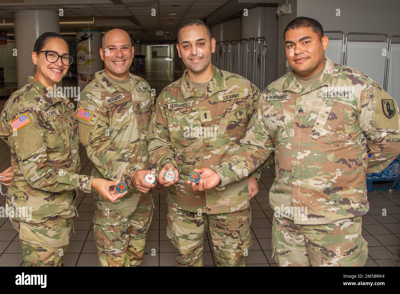From left, Spc. Zamia López, Sgt. 1st. Class Omar Rosario, 1st. Lt. José Hernandez, and Sgt. Julio Rodríguez show the coin of excellence received from Maj. Gen. John C. Andonie, deputy director of the Army National Guard, at Luis Muñoz Marín in Carolina, Puerto Rico, Feb. 24, 2022. The deputy director of the Army National Guard visited the island to learn about the Puerto Rico National Guard's COVID-19 operations. Stock Photo