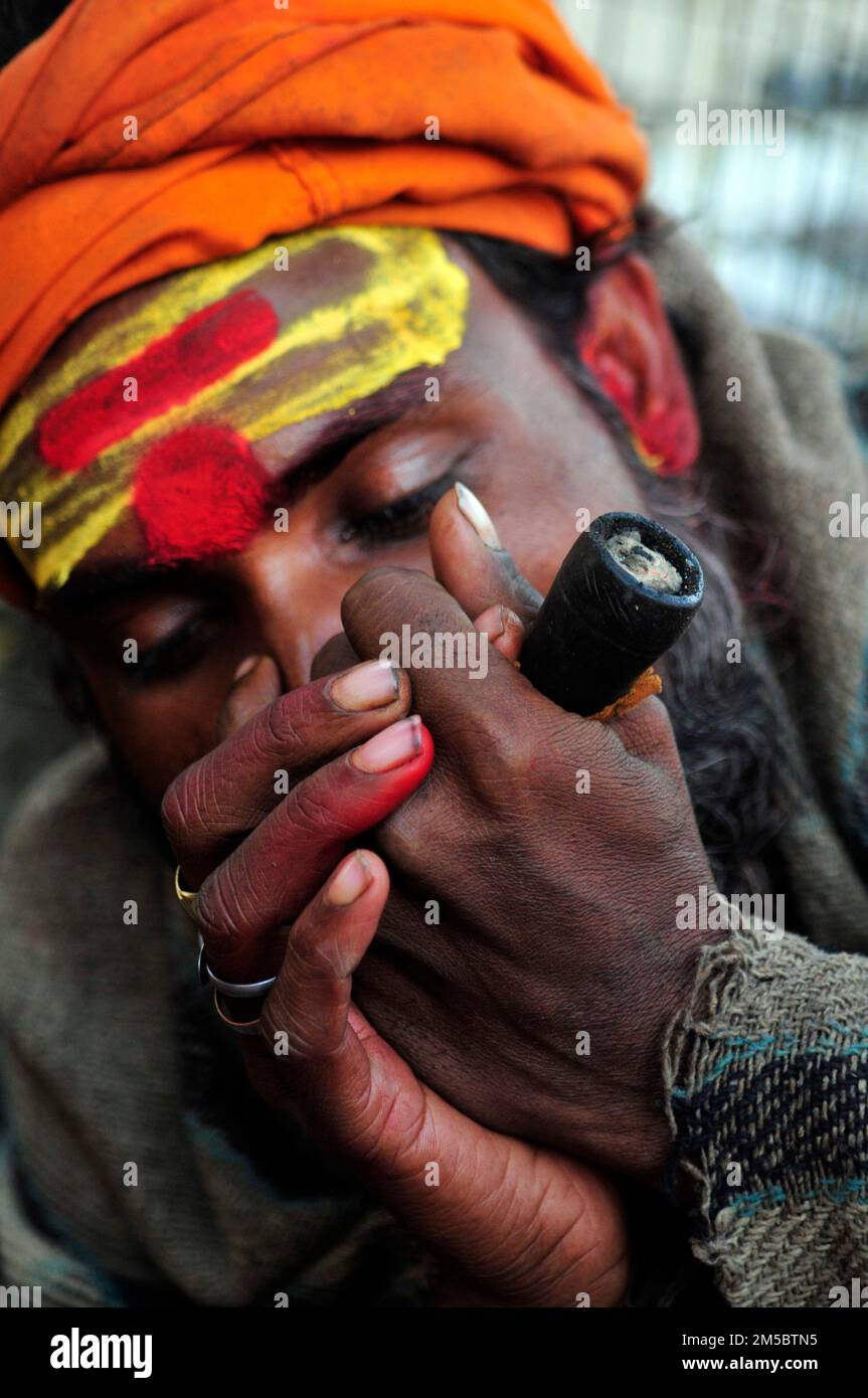 A Shaivite sadhu smoking chillum on the Mallick Ghat by the Hooghly river in Kolkata, India. Stock Photo