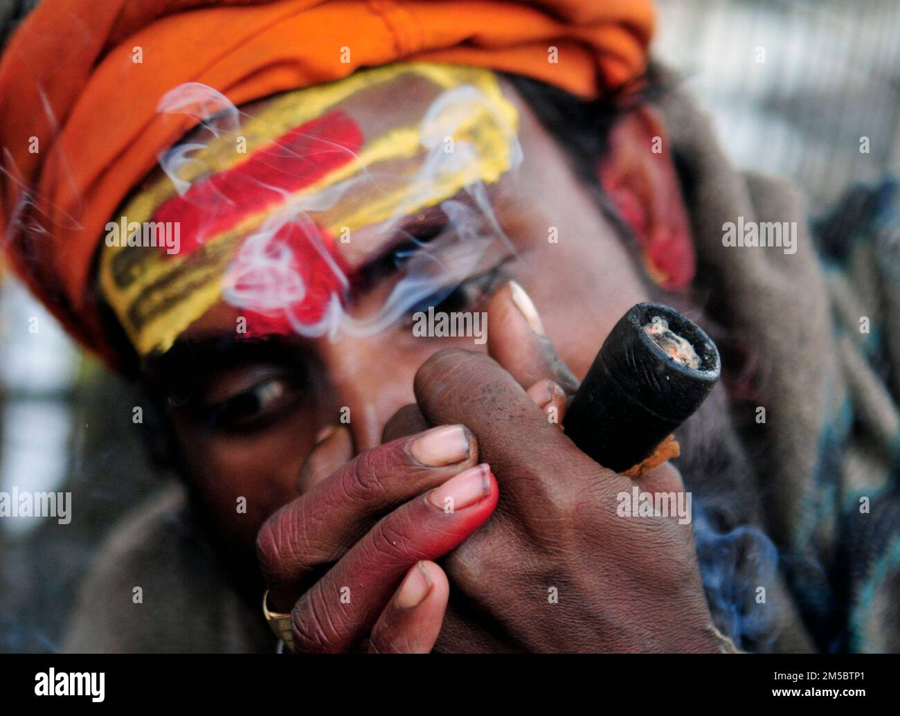 A Shaivite sadhu smoking chillum on the Mallick Ghat by the Hooghly river in Kolkata, India. Stock Photo