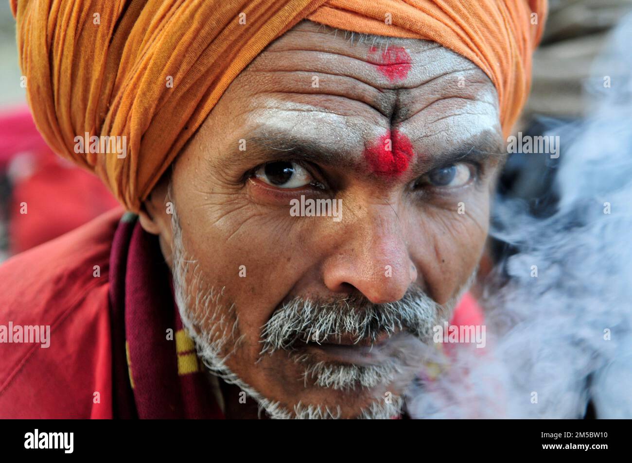 A Shaivite sadhu smoking chillum on the Mallick Ghat by the Hooghly river in Kolkata, India. Stock Photo