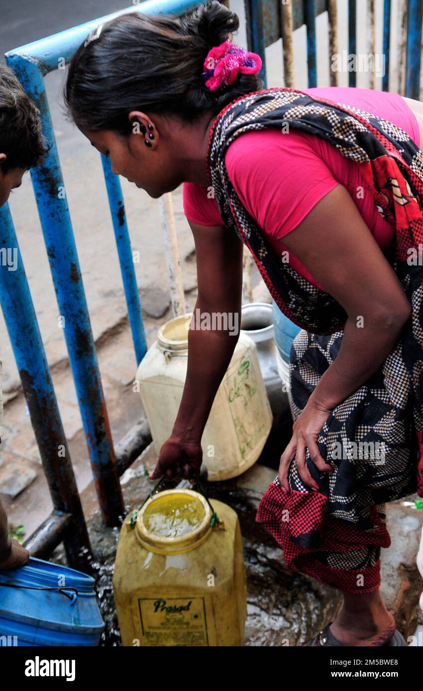 Local women fill jerrycans with water as there is no running water in their home in a slum in central Kolkata, India. Stock Photo