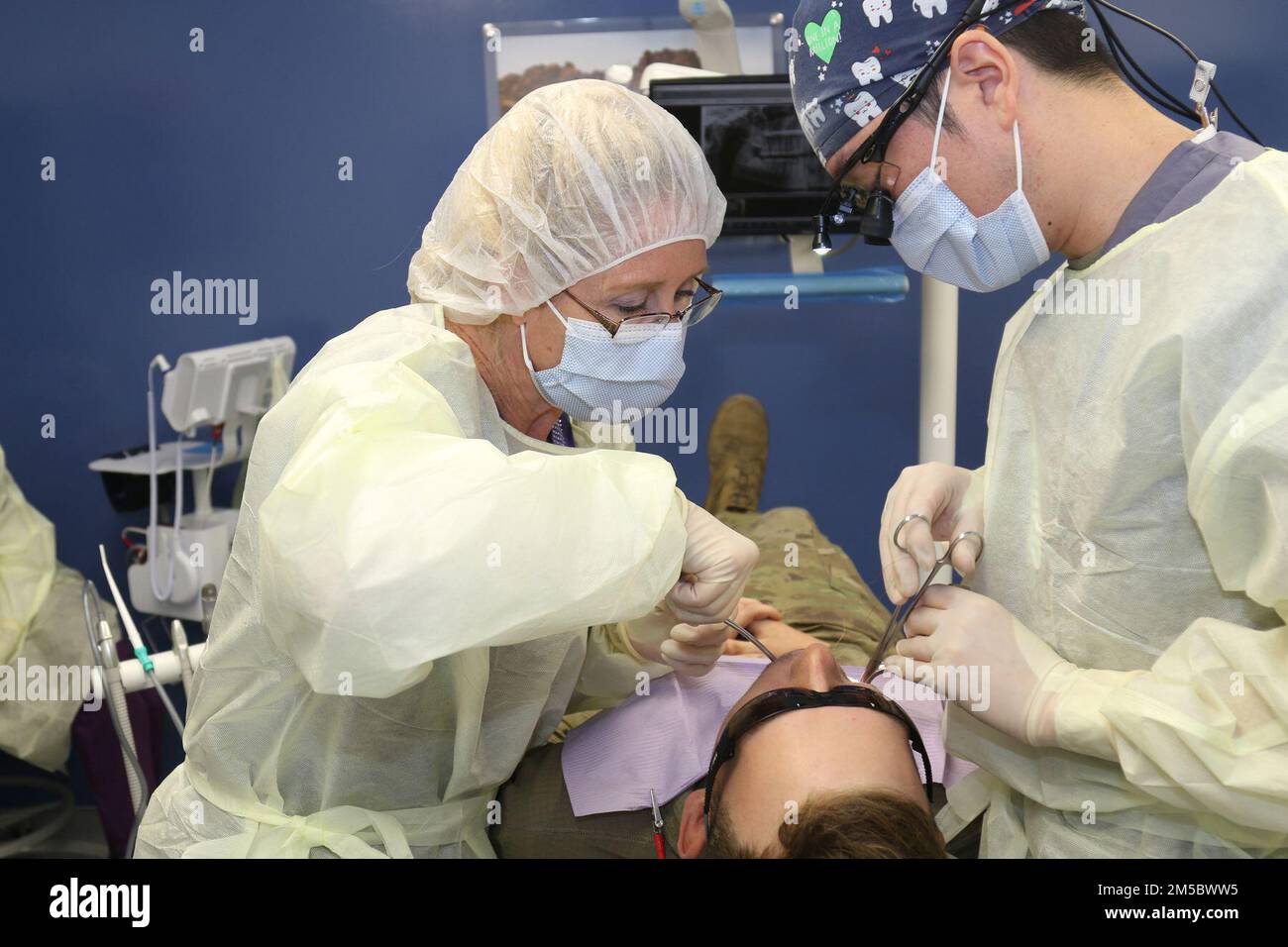 Stephanie Haydt (left), spouse of Brian Haydt, the command sergeant major of the National Training Center, assists Capt. Paul Chung (right), a general dentist with Fort Irwin Dental Command, Feb. 24, during a dental extraction at Shuttleworth Dental Clinic on Fort Irwin, Calif. Haydt is training with Fort Irwin Dental Command staff as part of the American Red Cross Dental Assistant Training program. (Photo by Kimberly Hackbarth/ Weed ACH Public Affairs Office) Stock Photo