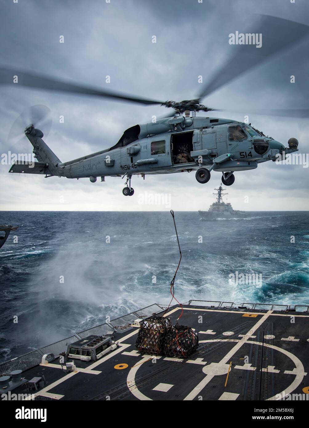 An MH-60R Sea Hawk helicopter, attached to Helicopter Maritime Strike Squadron (HSM) 48, delivers supplies to the guided-missile destroyer USS Delbert D. Black (DGG 119) during a vertical replenishment at sea with the replenishment oiler USNS John Lenthall (T-AO-189) while underway for Surface Warfare Advanced Tactical Training (SWATT). Delbert D. Black is part of Destroyer Squadron (DESRON) 26 which supports Carrier Strike Group (CSG) 10. SWATT is led by the Naval Surface and Mine Warfighting Development Center (SMWDC) and is designed to increase warfighting proficiency, lethality, and intero Stock Photo