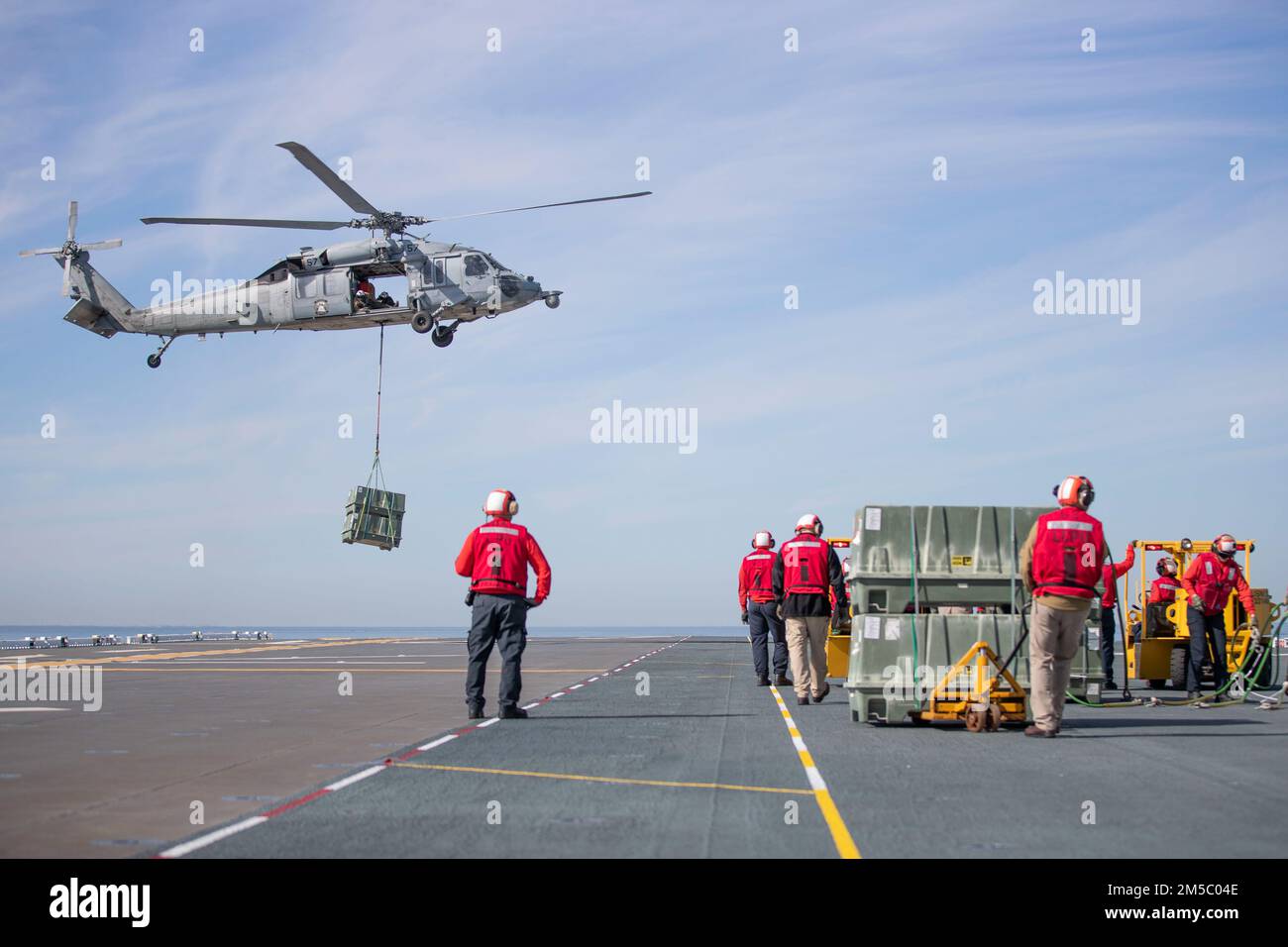 220225-N-CZ759-1211 PACIFIC OCEAN (Feb. 25, 2022) – An MH-60S Sea Hawk helicopter assigned to Helicopter Sea Combat Squadron (HSC) 23 delivers a pallet of ammunition to amphibious assault ship USS Tripoli’s (LHA 7) flight deck, Feb. 25. Tripoli is underway conducting routine operations in U.S. 3rd Fleet. Stock Photo