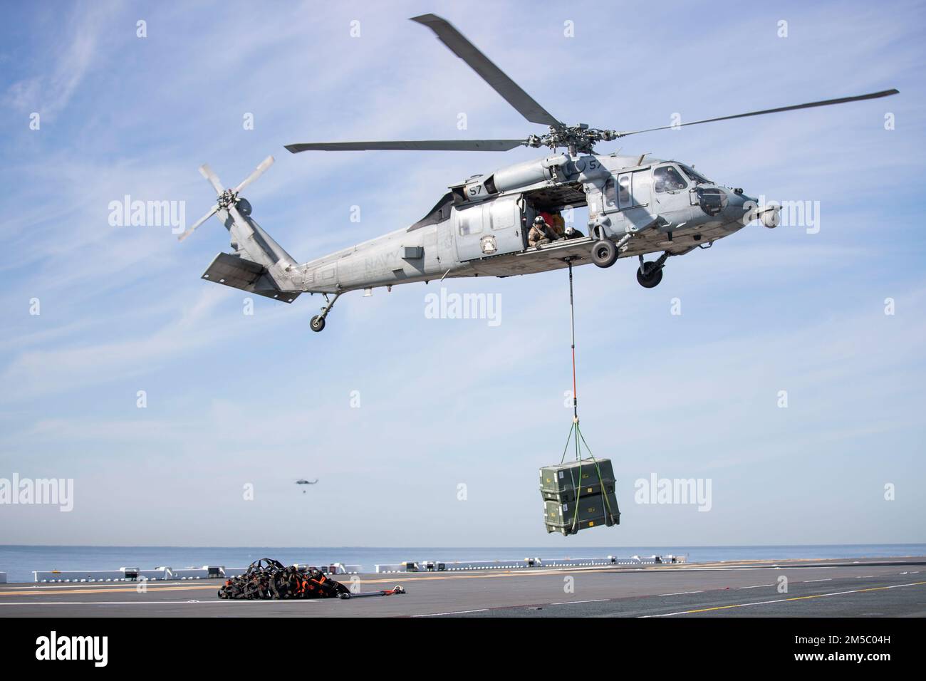 220225-N-CZ759-1137 PACIFIC OCEAN (Feb. 25, 2022) – An MH-60S Sea Hawk helicopter assigned to Helicopter Sea Combat Squadron (HSC) 23 delivers a pallet of ammunition to amphibious assault ship USS Tripoli’s (LHA 7) flight deck, Feb. 25. Tripoli is underway conducting routine operations in U.S. 3rd Fleet. Stock Photo