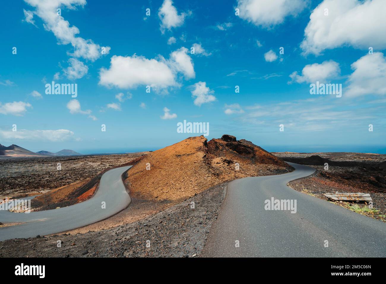 Asphalt road in volcanic arid landscape of Timanfaya National Park, Lanzarote, Canary Islands, Spain Stock Photo