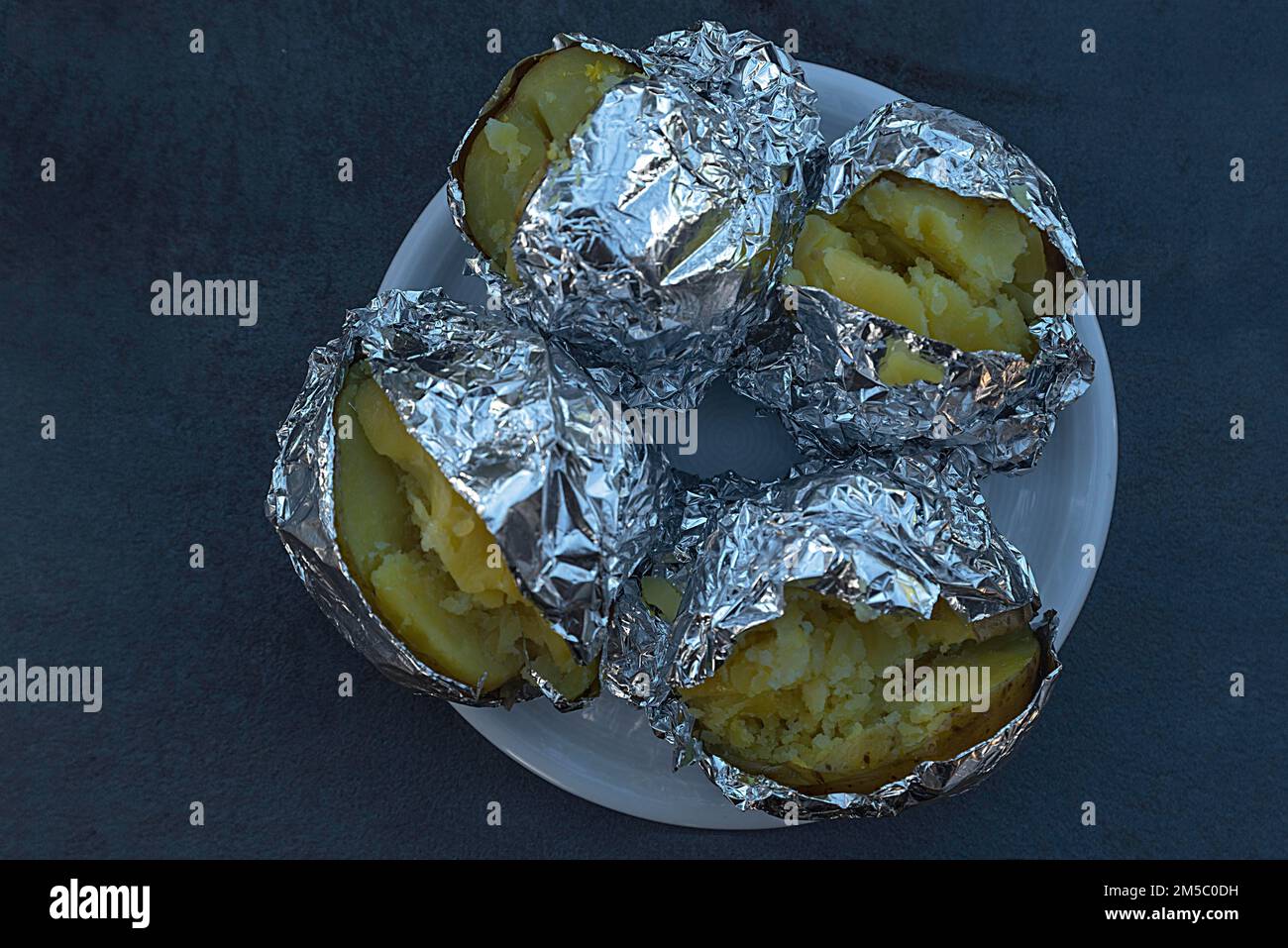 Jacket potatoes wrapped in aluminium foil, Bavaria, Germany Stock Photo