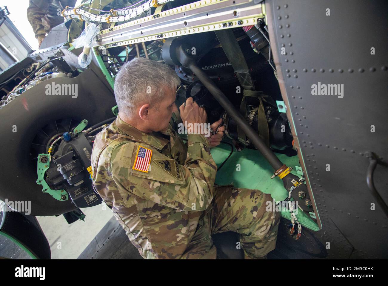 Maj. Gen. Charles Costanza, the 3rd Infantry Division commanding general, installs a generator on an AH-64 Apache helicopter at Hunter Army Airfield, Georgia, Feb. 25. Maj. Gen. Costanza visited the Bravo Co., 603rd Aviation Support Battalion, 3rd Combat Aviation Brigade, 3rd ID to observe the company's aviation support operations and aircraft phase maintenance. Stock Photo