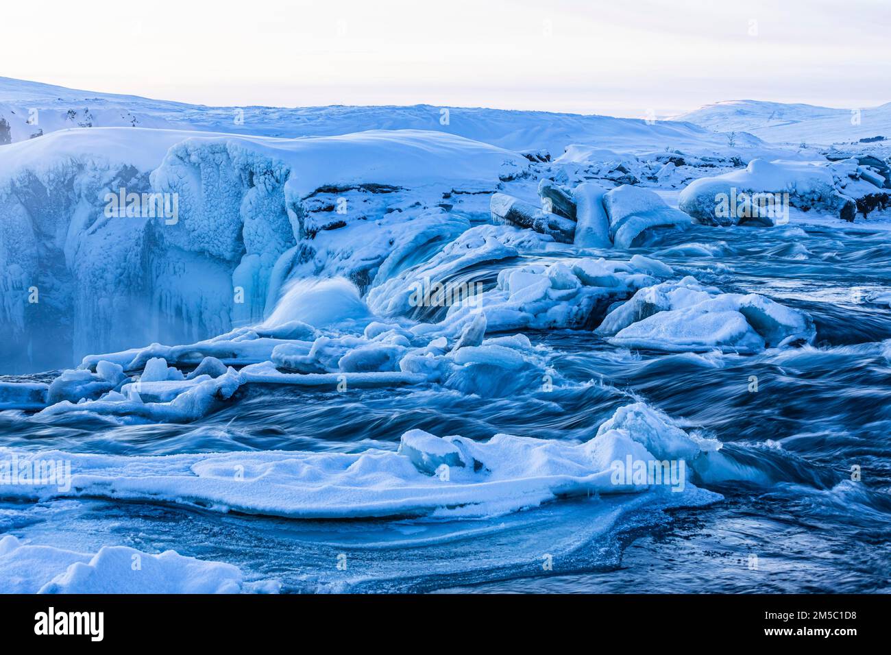 Icefall at the edge of the Godafoss waterfall at dawn, snow-covered landscape, Northern Iceland Eyestra, Iceland Stock Photo