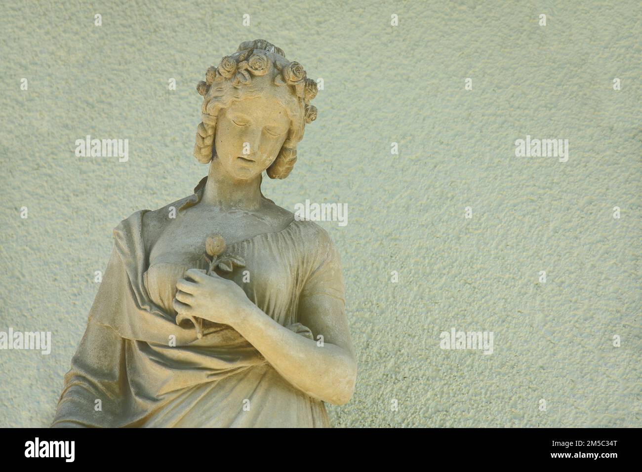 Sculpture of a woman with hair ornament and rose, flower in arm, holding hand, stone, yellow, monochrome, Opelvillen, Villa Wenske, Opelvilla Stock Photo