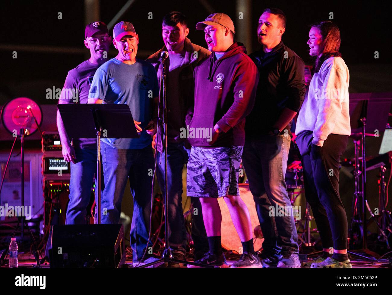 Service members from the 378th Air Expeditionary Wing perform live band karaoke during a U.S. Air Forces Central Band concert at Prince Sultan Air Base, Kingdom of Saudi Arabia, Feb. 27, 2022. The AFCENT Band supports the morale of deployed troops by playing various concerts around the region. Stock Photo