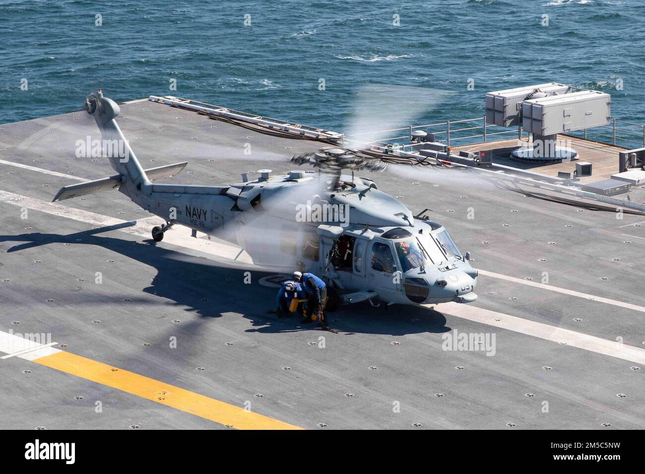 An MH-60S Sea Hawk helicopter attached to the “Knights” of Helicopter Sea Combat Squadron (HSC) 22 prepares to take off of the flight deck of USS Gerald R. Ford (CVN 78), Feb. 28, 2022. Ford is underway in the Atlantic Ocean after completing the industrial portion of a six-month Planned Incremental Availability (PIA). Stock Photo