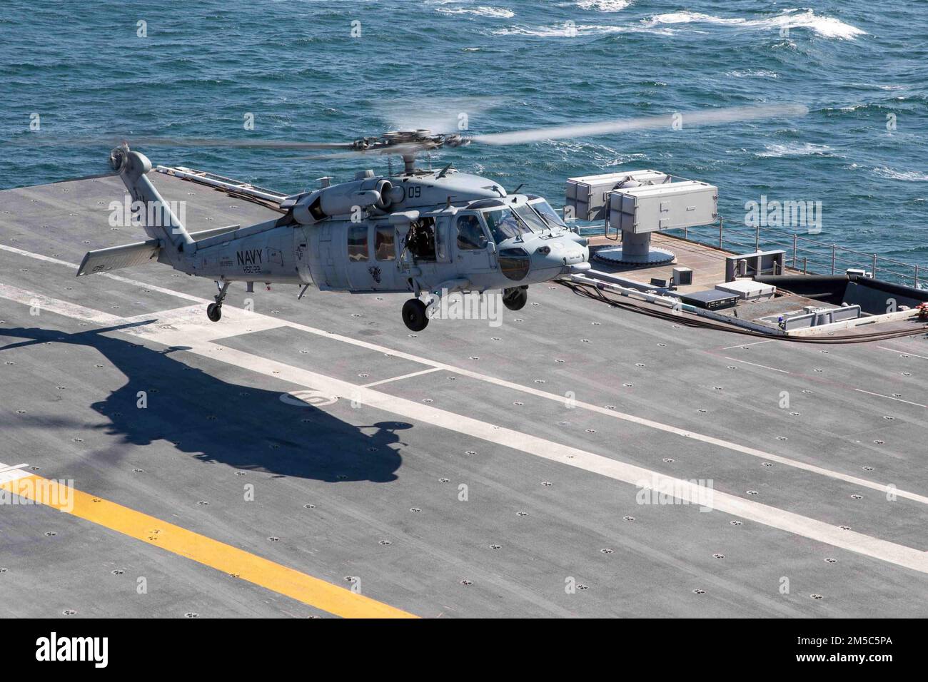 An MH-60S Sea Hawk helicopter attached to the “Knights” of Helicopter Sea Combat Squadron (HSC) 22 takes off of the flight deck of USS Gerald R. Ford (CVN 78), Feb. 28, 2022. Ford is underway in the Atlantic Ocean after completing the industrial portion of a six-month Planned Incremental Availability (PIA). Stock Photo
