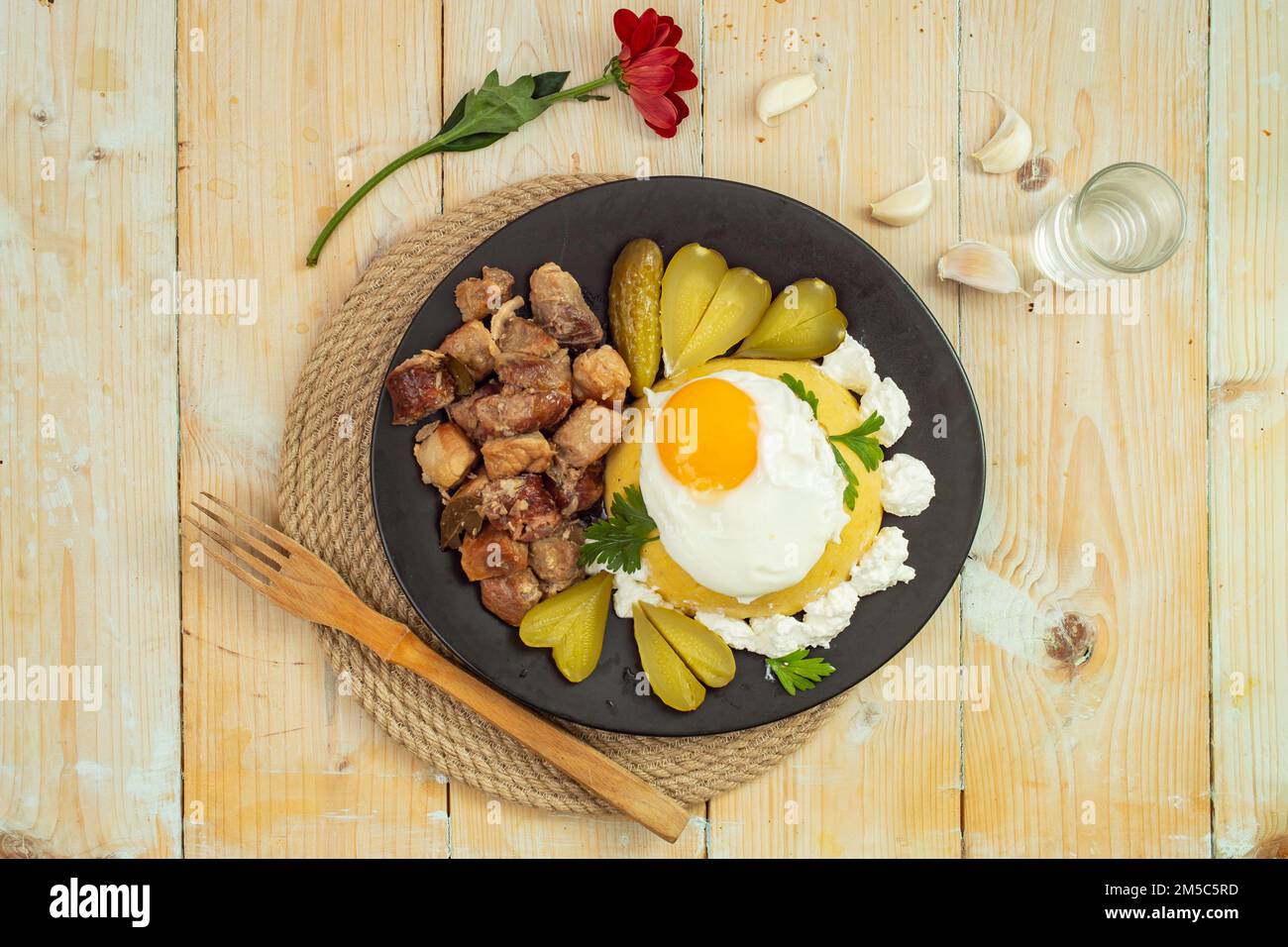 Romanian traditional dish  'Tochitura moldoveneasca', Recipe made with pork meat and sausages, Cheese, egg and ' mamaliga', flat lay close up, on a bl Stock Photo