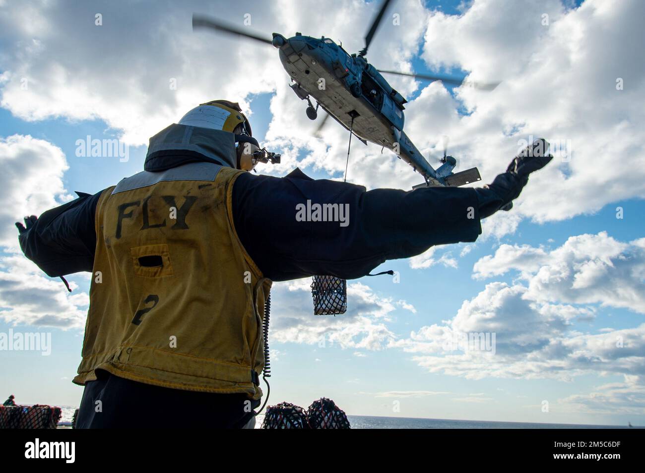 220228-N-PG226-1221 ADRIATIC SEA (Feb 28, 2022) Aviation Boatswain's Mate (Handling) 2nd Class Dagnan Vissoh, from Abidjan, Ivory Coast, directs the pilot of an MH-60S Sea Hawk helicopter, attached to the 'Dragonslayers' of Helicopter Sea Combat Squadron (HSC) 11, on the flight deck of the Nimitz-class aircraft carrier USS Harry S. Truman (CVN 75) during a replenishment-at-sea, Feb 28, 2022. The Harry S. Truman Carrier Strike Group is on a scheduled deployment in the U.S. Sixth Fleet area of operations in support of U.S., allied and partner interests in Europe and Africa. Stock Photo
