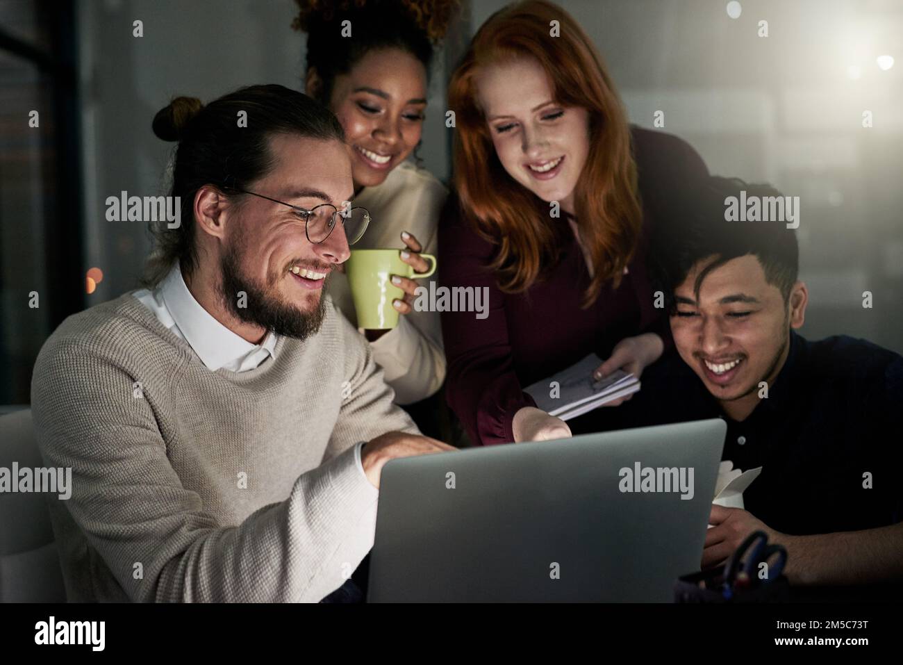 Designing is what makes them happy. a group of young designers working late in the office. Stock Photo