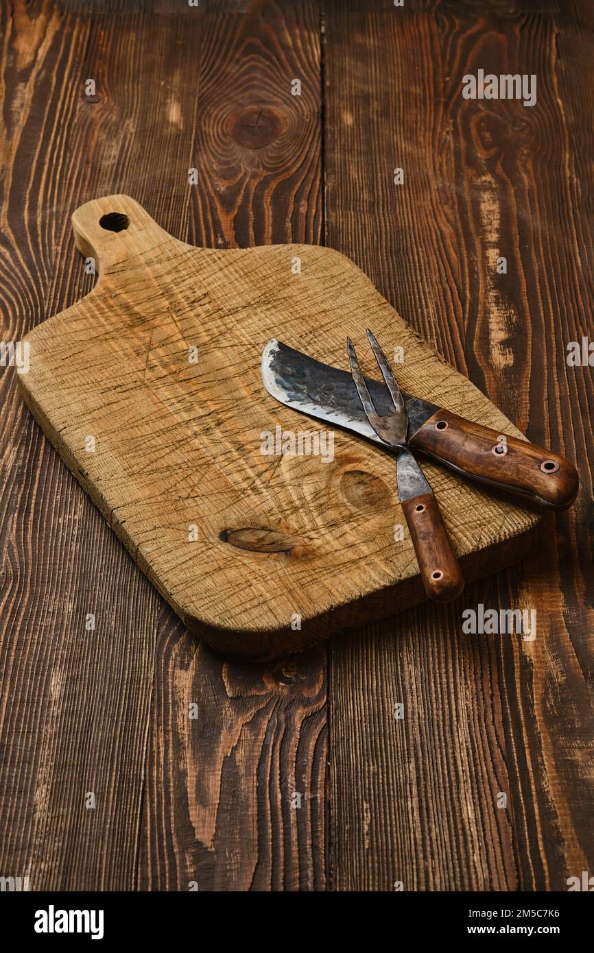 Rustic old cutting board with handmade knife and fork Stock
