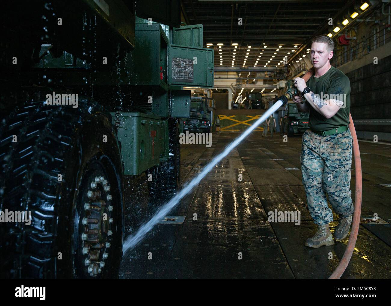 U.S. Marine Corps Cpl. Jordan Zubieta, a High Mobility Artillery Rocket System operator with Combat Logistics Battalion (CLB) 31, sprays tires during a truck wash down aboard USS Green Bay, Gulf of Thailand, Feb. 28, 2022. The 31st MEU is operating aboard the ships of the America Amphibious Strike Group in the 7th fleet area of operations to enhance interoperability with allies and partners and serve as a ready response to defend peace and stability in the Indo–Pacific Region. Stock Photo