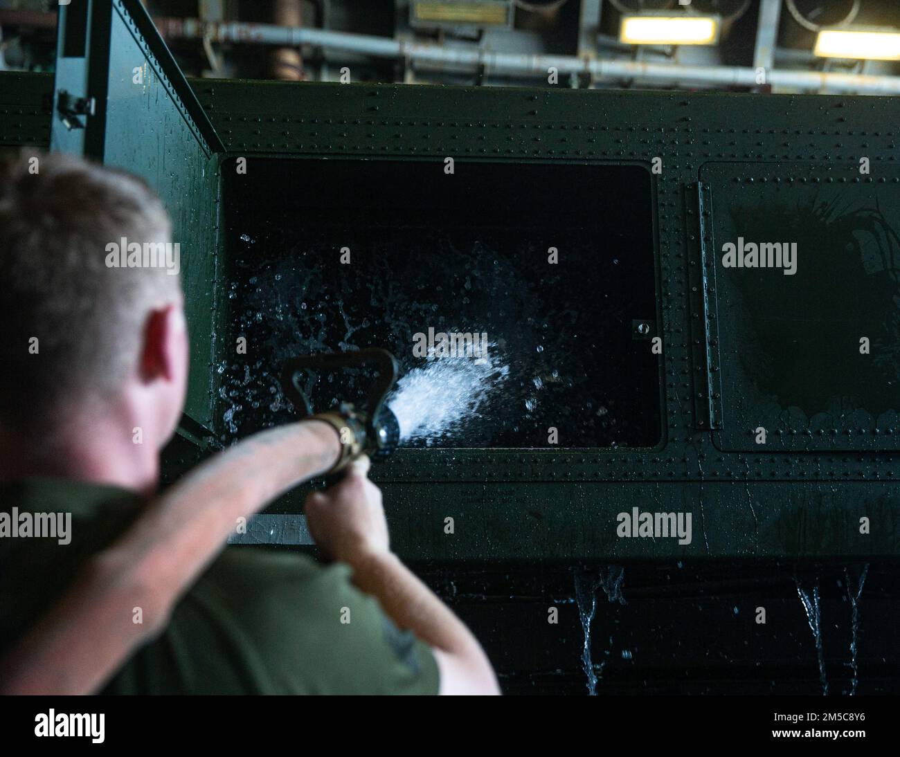 A U.S. Marine with Combat Logistics Battalion (CLB) 31, washes the inside of a truck during a truck wash down aboard USS Green Bay, Gulf of Thailand, Feb. 28, 2022. The 31st MEU is operating aboard the ships of the America Amphibious Strike Group in the 7th fleet area of operations to enhance interoperability with allies and partners and serve as a ready response to defend peace and stability in the Indo–Pacific Region. Stock Photo
