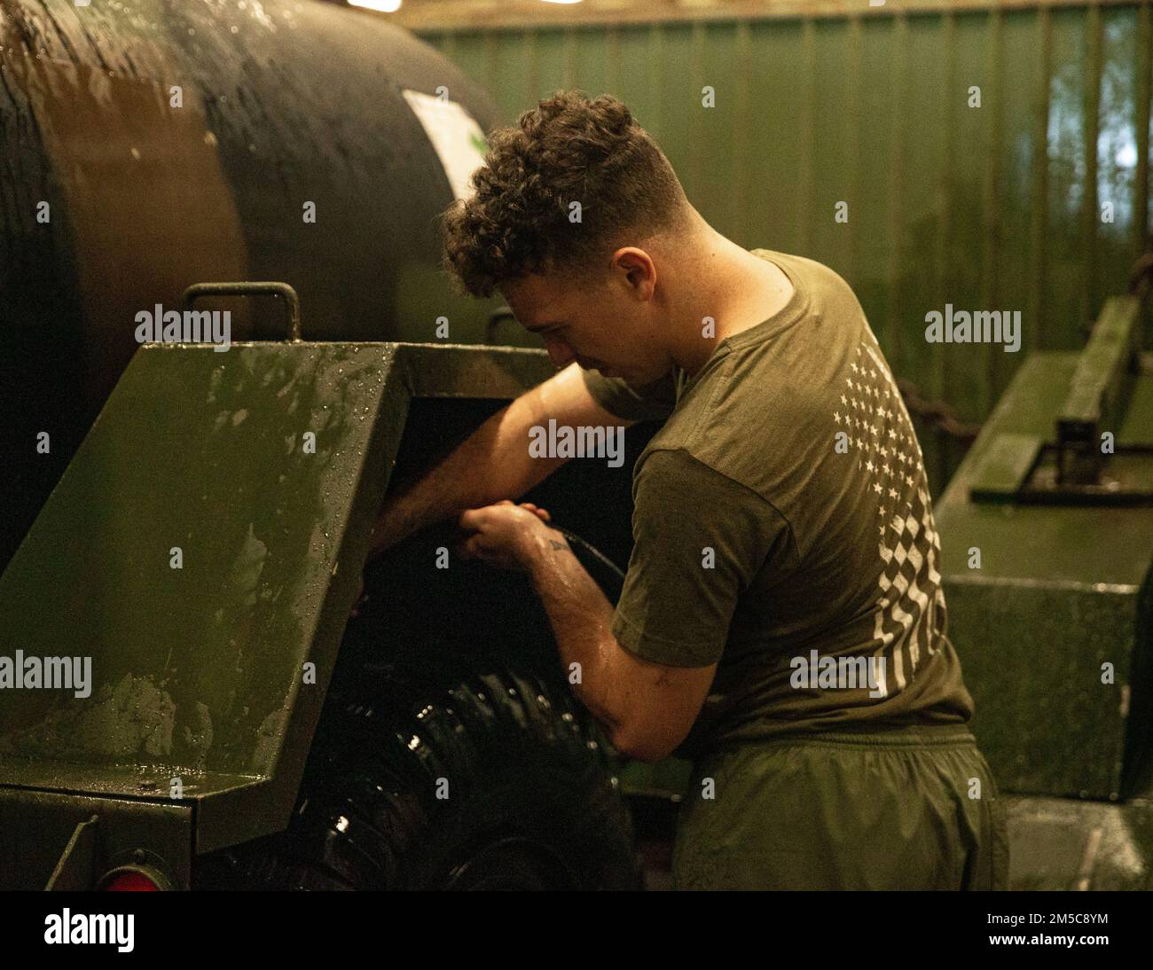 U.S. Marine Corps Cpl. Cameron Huffman, a Light Armored Vehicle mechanic     with Combat Logistics Battalion (CLB) 31, washes underneath a water buffalo during a truck wash down aboard USS Green Bay, Gulf of Thailand, Feb. 28, 2022. The 31st MEU is operating aboard the ships of the America Amphibious Strike Group in the 7th fleet area of operations to enhance interoperability with allies and partners and serve as a ready response to defend peace and stability in the Indo–Pacific Region. Stock Photo