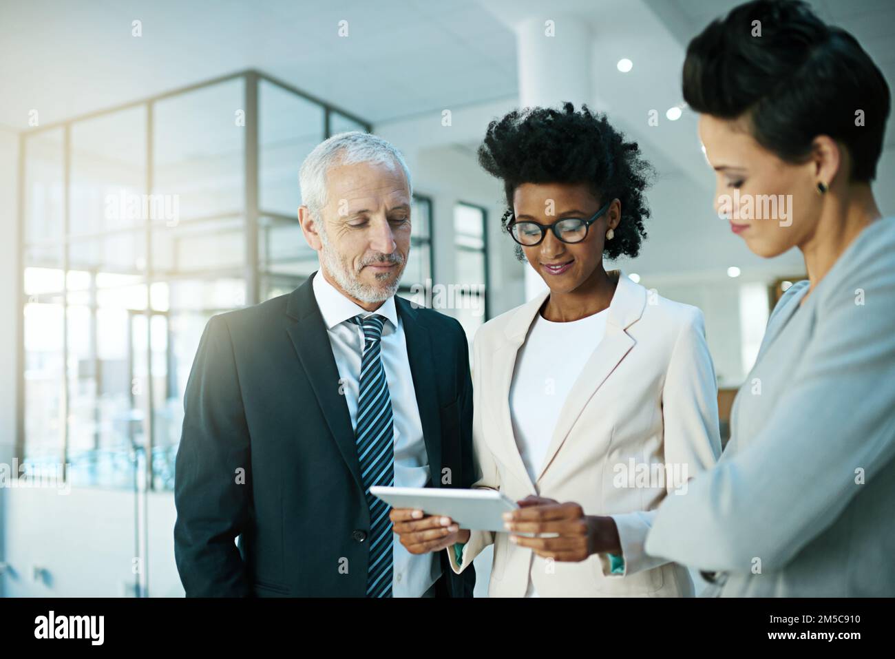 Updating the team as to where they are. a business team using a digital tablet while having an informal meeting. Stock Photo