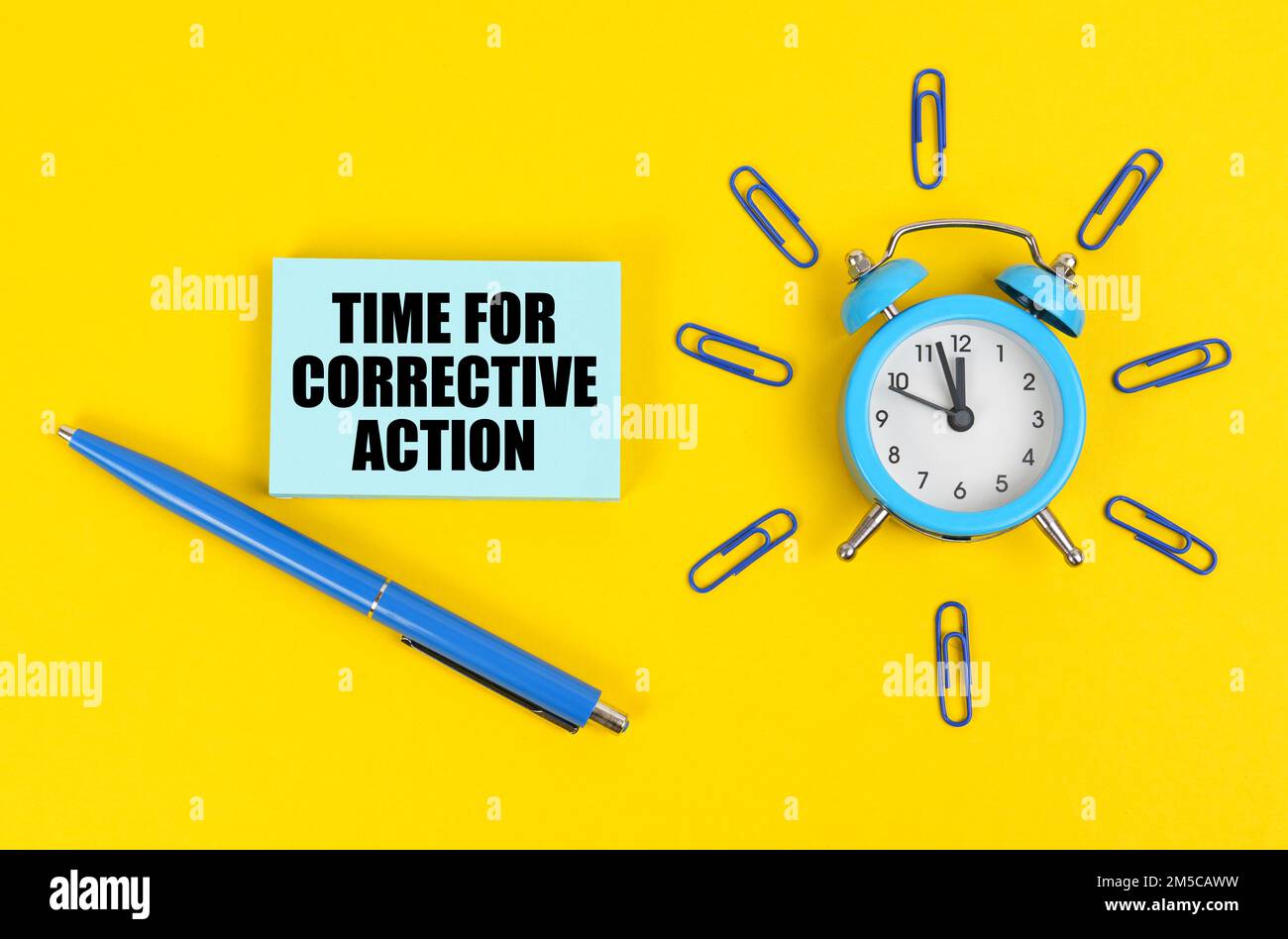 Business and industry concept. On the yellow surface there is an alarm clock, a pen and stickers with the inscription - Time for Corrective Action Stock Photo
