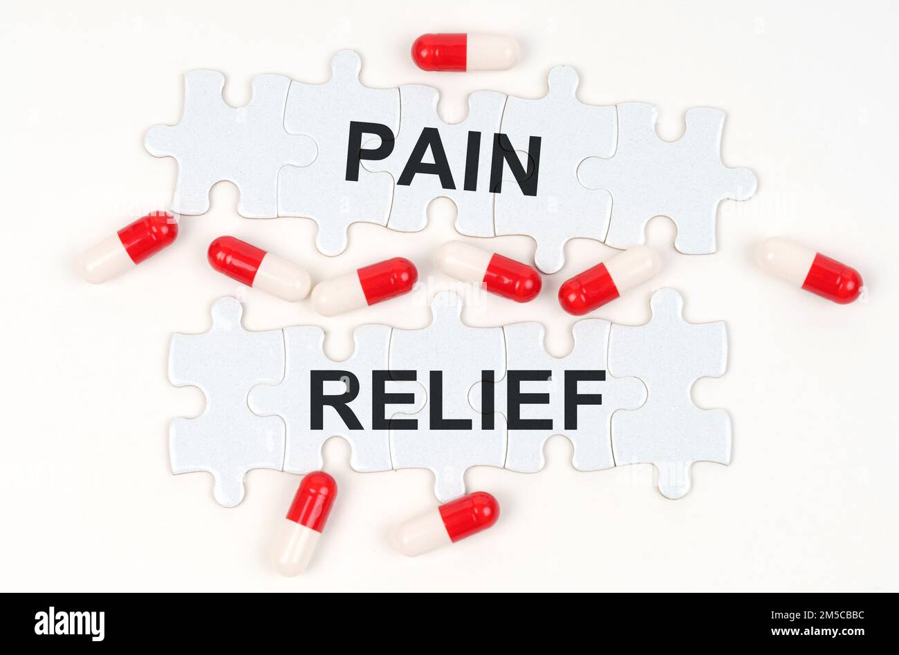Medical concept. On a white surface, tablets and puzzles with the inscription - PAIN RELIEF Stock Photo