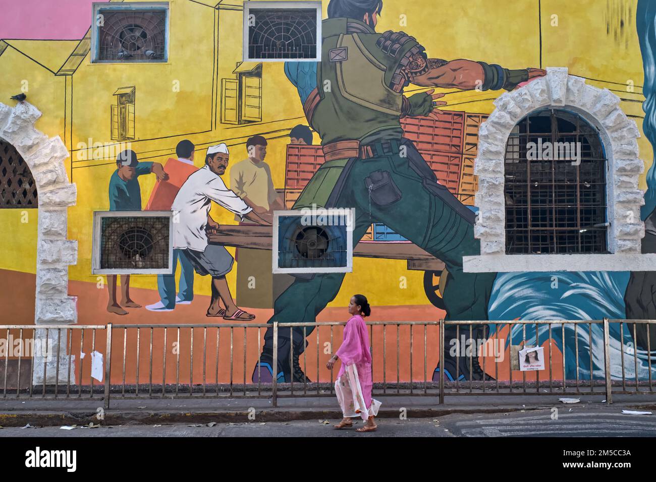 A woman passes a colorful wall painting at Sassoon Docks, Colaba, Mumbai, India Stock Photo