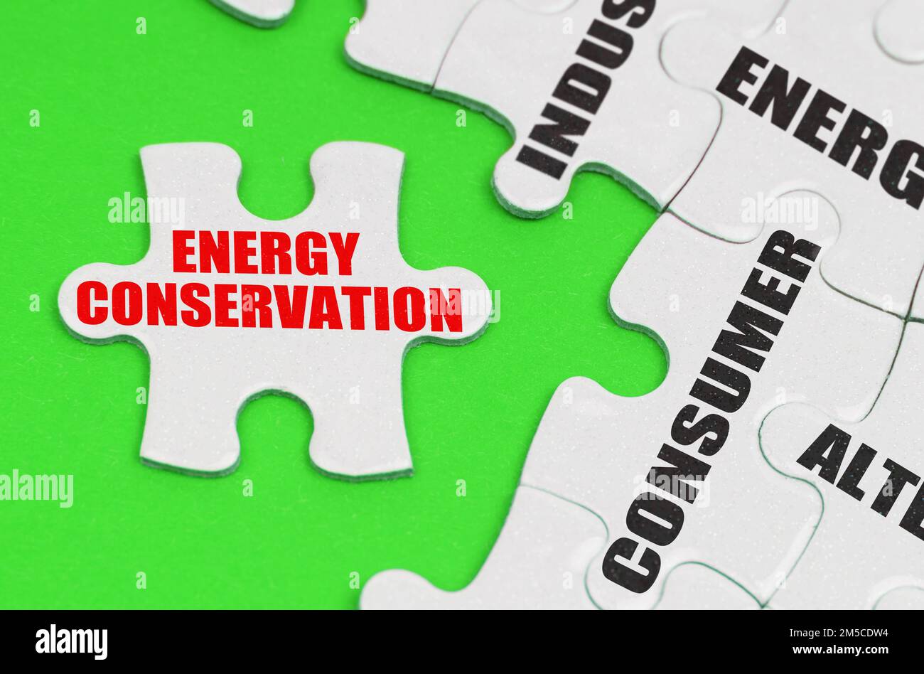 Energy concept. On a green surface there are white puzzles with inscriptions, on a separate puzzle there is an inscription - Energy Conservation Stock Photo