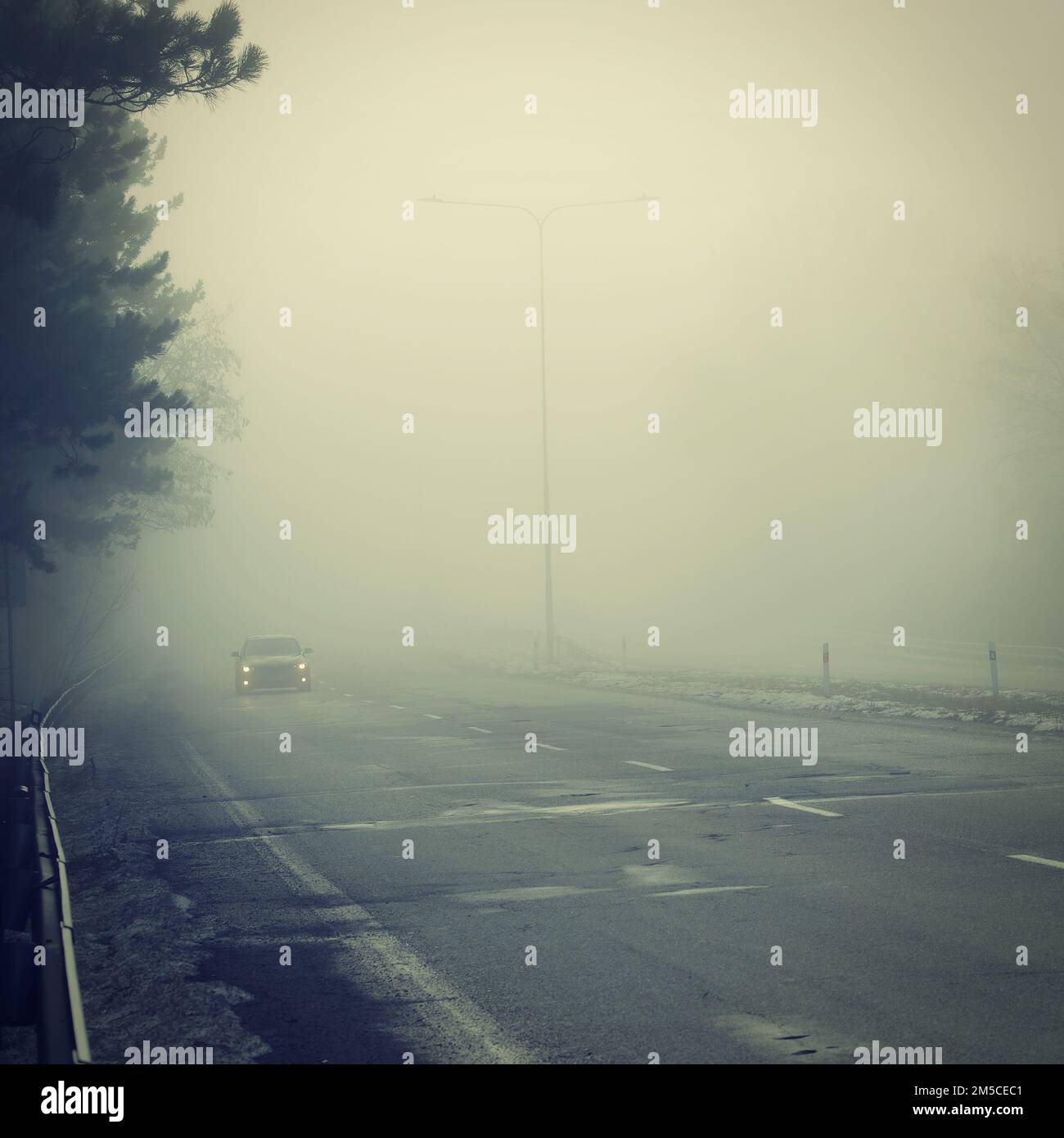 Bad weather driving - foggy hazy country road. Motorway - road traffic. Winter time. Stock Photo