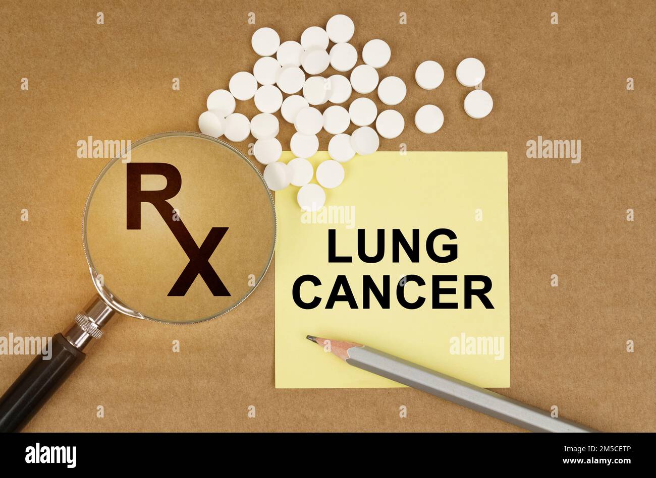 Medical concept. On the table are pills, a magnifying glass, pencils and a sticker with the inscription - LUNG CANCER Stock Photo