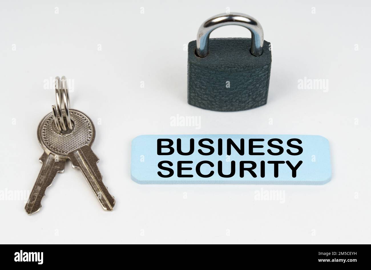 The concept of security in business. On a white surface there is a lock, keys and a blue sign with the inscription - Business security Stock Photo
