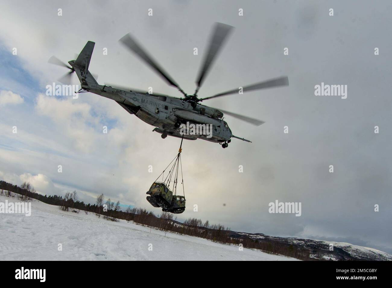 A CH-53E Super Stallion with Marine Heavy Helicopter Squadron 366 (HMH-366), 2nd Marine Aircraft Wing, conducts a lift with a Norwegian Bandvagn 206 in preparation for Exercise Cold Response 2022, Bardufoss, Norway, Feb. 28, 2022. Exercise Cold Response '22 is a biennial Norwegian national readiness and defense exercise that takes place across Norway, with participation from each of its military services, as well as from 26 additional North Atlantic Treaty Organization (NATO) allied nations and regional partners. Stock Photo
