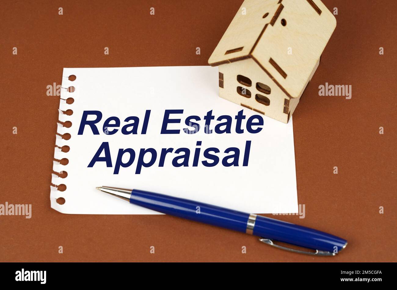 Business concept. On a brown surface is a house, a pen and a notepad with the inscription - Real Estate Appraisal Stock Photo