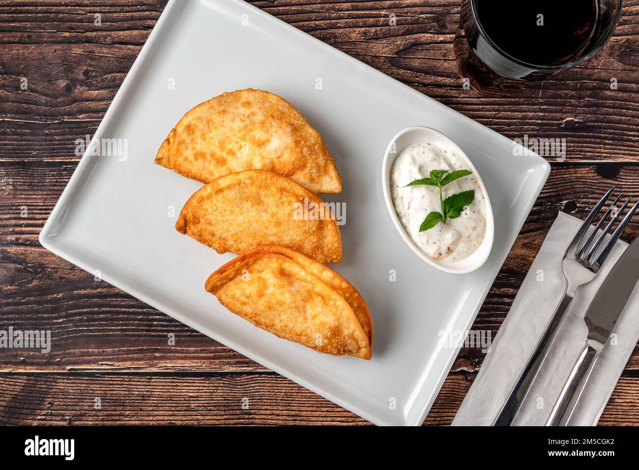 Beef Cheburek on a wooden table. Deep Fried Beef Dumplings with meat and onions. Turkish name Ci Borek or Cig Borek Stock Photo