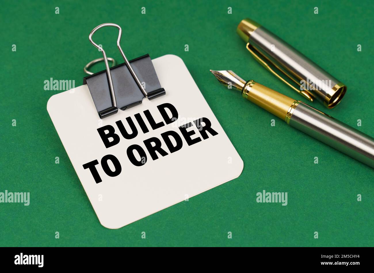 Business and industry concept. On a green surface, a pen and a sheet of paper with the inscription - Build to Order Stock Photo